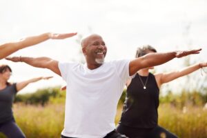 People practising yoga together outdoors on a summer morning